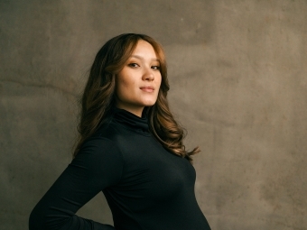 a woman holding her belly in front of a grey background