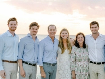 a family of six standing on a beach at dusk