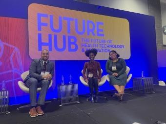 three young people sitting together in front of a sign that reads "Future Hub"