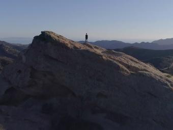 a figure stands on a mountain 