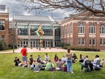 Outdoor gathering of students outside Wall Center with Shonibare sculpture in the background