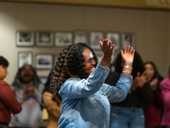 a young Black woman dances in a crowd while smiling