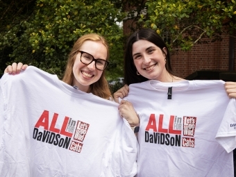 two young women holding white tee shirts