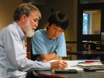 A professor advising a student sitting at a desk