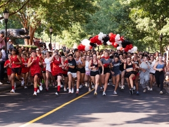 a group of young women run while smiling on a road