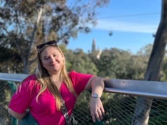 a young white woman stand on an outdoor balcony