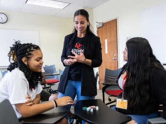 a faculty member talks to two students in a classroom