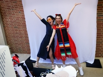 a group of two women posing together in front of a sign