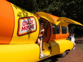 Emily Schmidtt '23 gives a thumbs-up from the open door of the parked Weinermobile