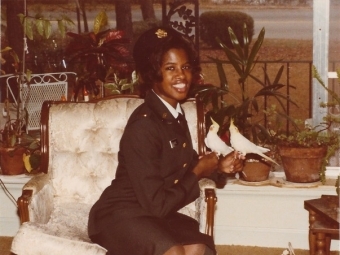 a young Black woman in uniform sitting on a white chair