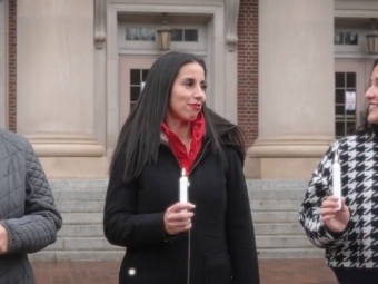 three young women walk together talking and holding candles