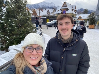 an older white woman and a younger white man smile in front of a snowy landscape
