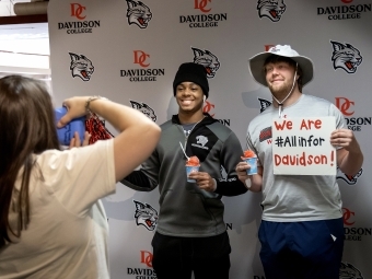 Two students pose with sno-cones and Davidson-themed signs at All In for Davidson