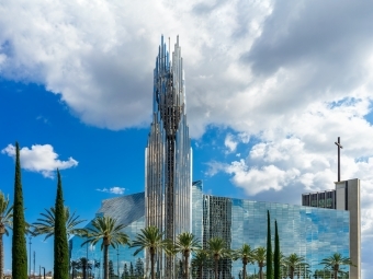 a large glass building surrounded by palm trees on a sunny day