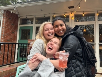 a group of young women smiling and holding a coffee