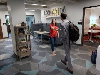 a woman greets a young man in an office suite