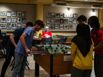 a group of students stand around a foosball table playing