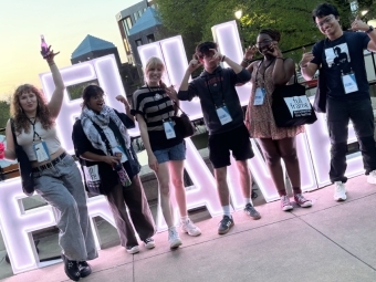 a group of young people smile and pose in front of a sign that reads "Full Frame"