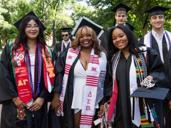 Commencement 2025 grads smiling with their diplomas 