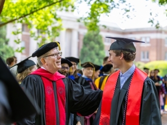 Commencement 2025 President Doug Hicks speaking to student