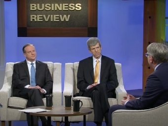 a group of three older white men sit around a TV set talking