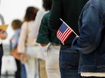 Person in line to vote holding American flag