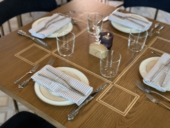 a wooden table is set with napkins, plates, cutlery and glasses
