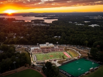 an aerial view of a football stadium as the sun sets in the distance over a lake