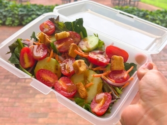 a plastic container holding salad outside