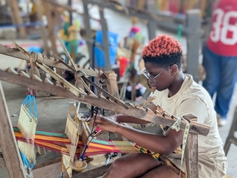 a young person works at a loom 