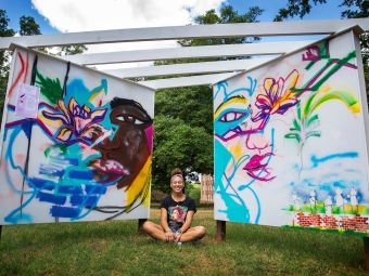 Makayla Binter sitting between her Mural Project