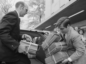 Two men handling documents of edited versions of many of President Nixon's Watergate conversations