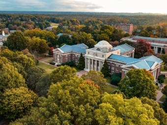 an aerial view of a college campus with brick buildings, green trees and a lake in the distance