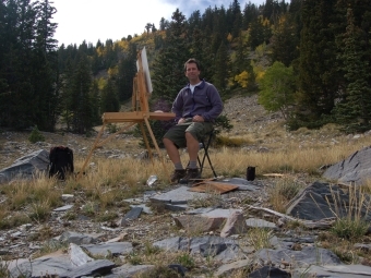 a young man paints in a forest