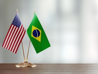 two small flags from the US and Brazil on a desk