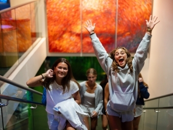 young women jump and smile in a museum