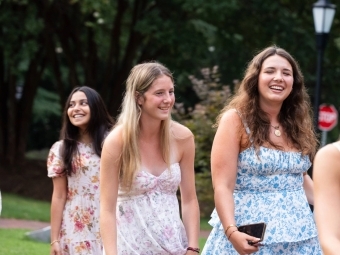 a group of young women smile while walking on college campus