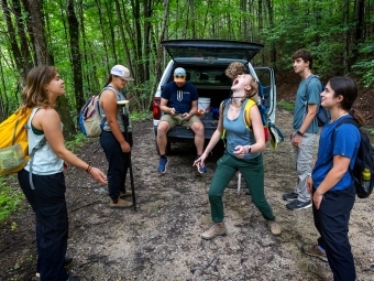 a group of students play and smile in the woods