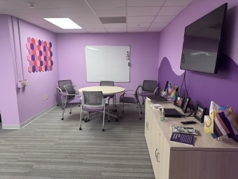 a purple painted room with a circular table and chairs as well as a tv and console