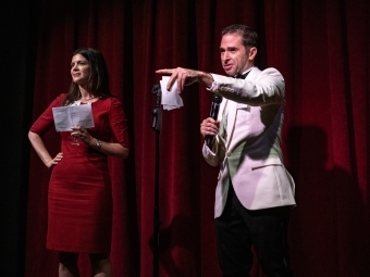 Randall Mardus '99 in a white suit and another alum onstage in a red dress