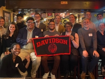 Group of alums in New York City holding a Davidson pennant flag