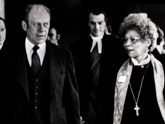 a Black woman walks and talks with an older white man in a black and white photograph