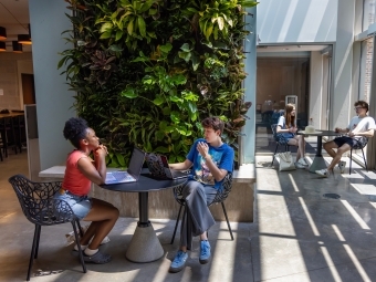 two people meet over laptops and notebooks in a modern academic space