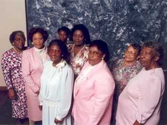 Group of black woman of varying ages wearing pink blazers