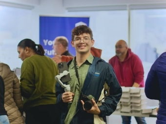 a young man with a camera and phone works media at an event