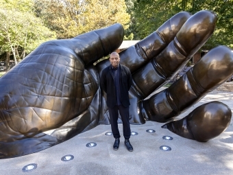 The artist, Hank Willis Thomas, stands in front of With These Hands at the dedication