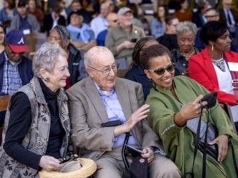 Two elderly white people and an adult black woman take a selfie at the dedication ceremony