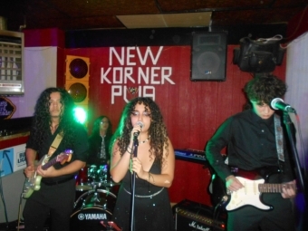 A group of students stand on a dimly lit stage with instruments