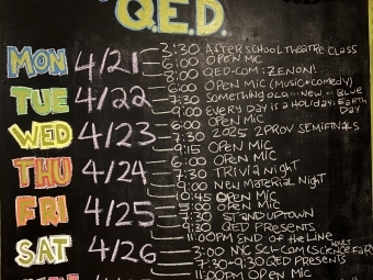 A colorful chalkboard that reads "This week at QED"