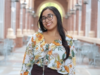 Headshot of young female student on campus, with long dark hair and glasses